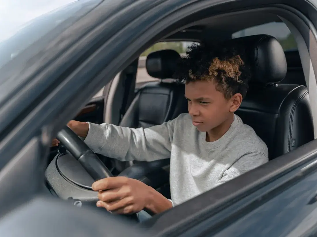 Jonge leerling oefent geconcentreerd met sturen tijdens een rijles